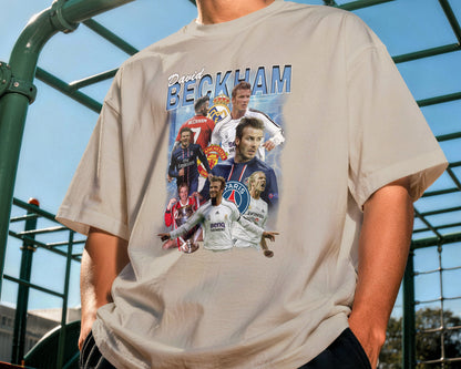 Person wearing a t-shirt with a collage of soccer players and the name 'Beckham' outdoors.