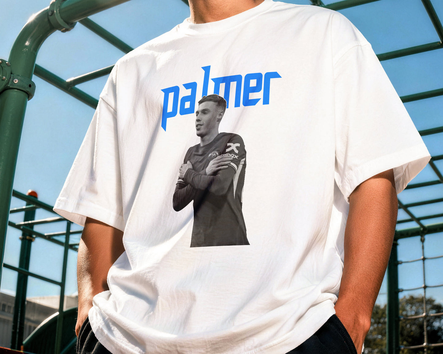 Person wearing a white t-shirt with a graphic and 'palmer' text outdoors.