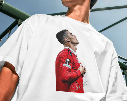 Person wearing a white t-shirt with a graphic of a soccer player in a red jersey.