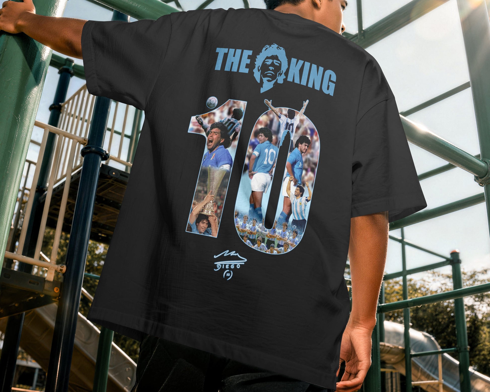 Person wearing a black t-shirt with a graphic design on the back, standing outdoors.