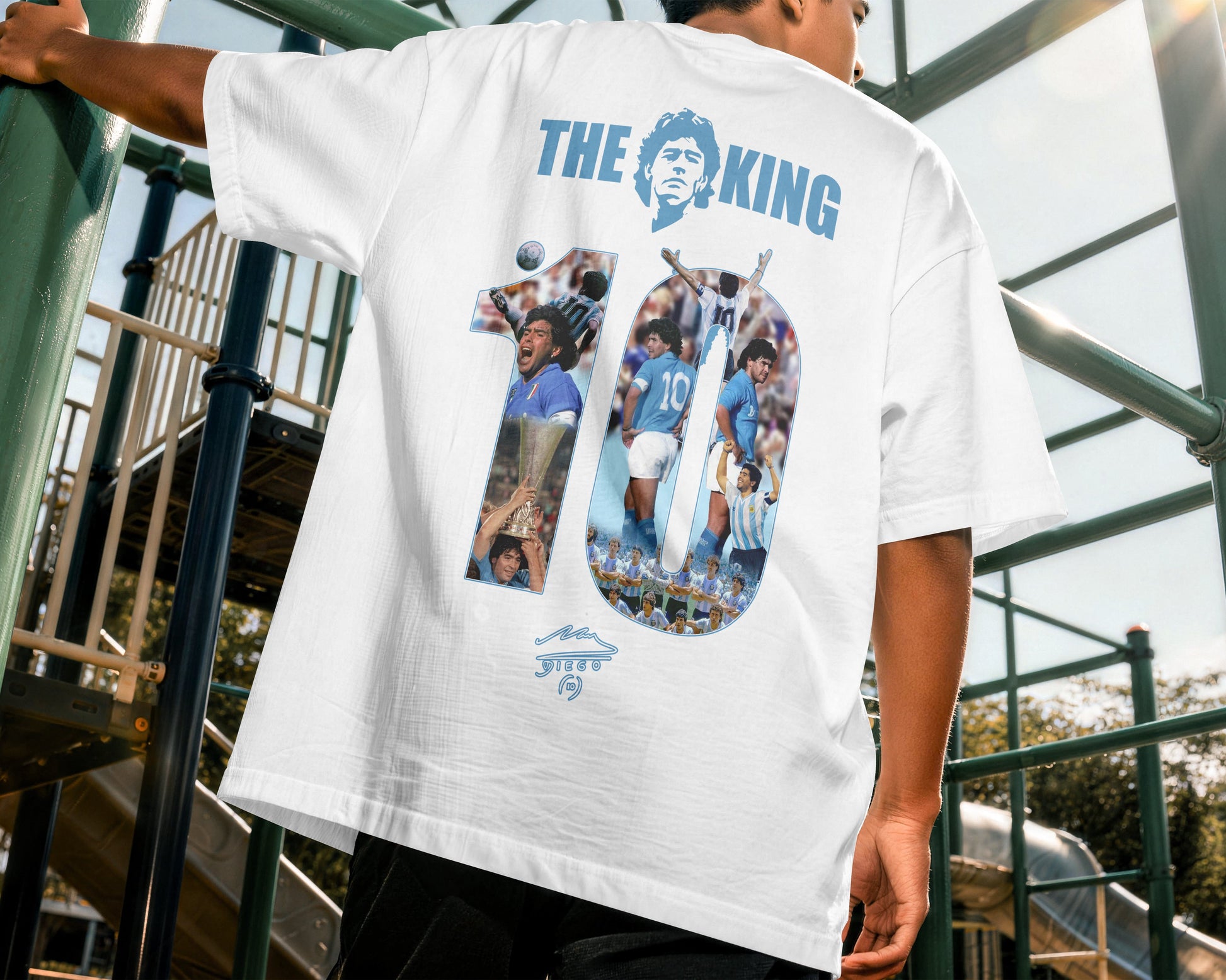 Person wearing a white t-shirt with 'The King' and number 10 design outdoors.