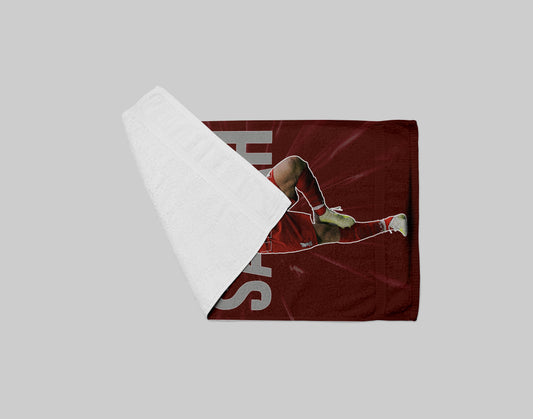 Folded red towel with a sports-themed design on a gray background